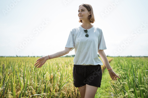 Young girl walking in the middle of the rice field with exotic view in the bright sunny day photo