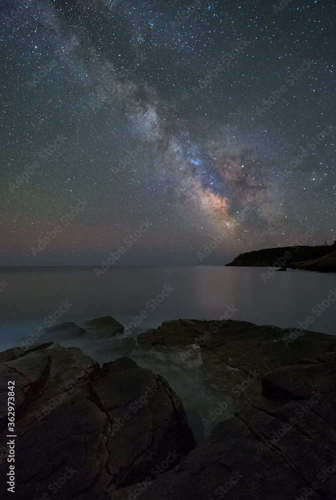 The Milky Way viewed from Monument Cove with Otter Cliff in the distant background in Maine's Acadia National Park. The Milky Way viewed from Monument Cove with Otter Cliff in the distant background in Maine's Acadia National Park.