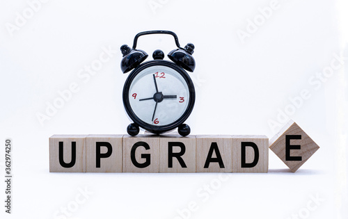 Business concept: Upgrade Word on Wooden Blocks and alarm-clock. Time is money. Time-limit.