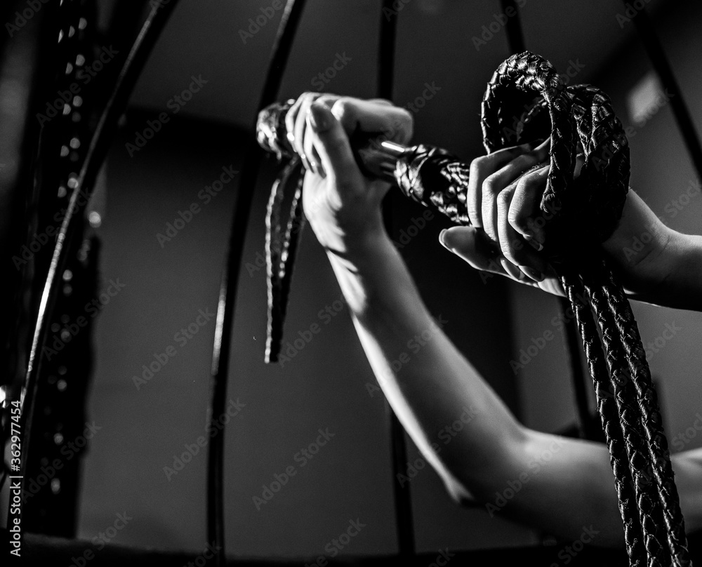 Foto De Female Hand With A Long Woven Leather Lash In A Cage Bdsm