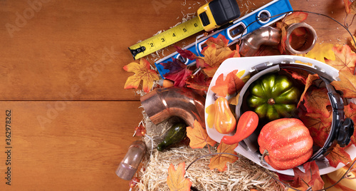 Happy Thanksgiving with construction tools, maple leaves and pumpkin on wood background.
Autumn composition with copy space. Plumber Thanksgiving. Top view.