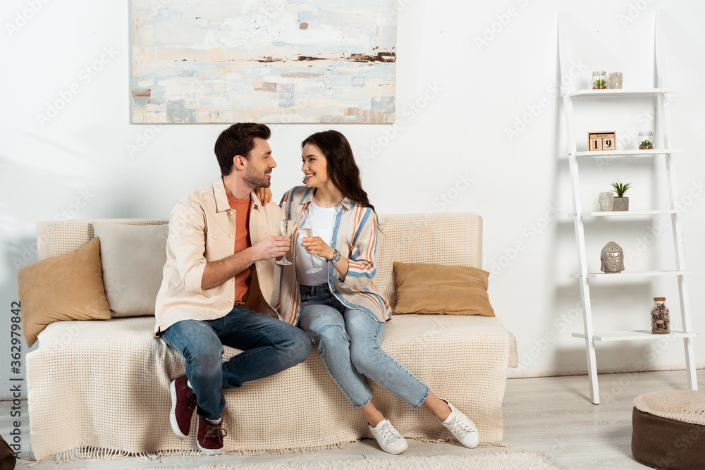Young couple smiling at each other while drinking champagne at home Young couple smiling at each other while drinking champagne at home