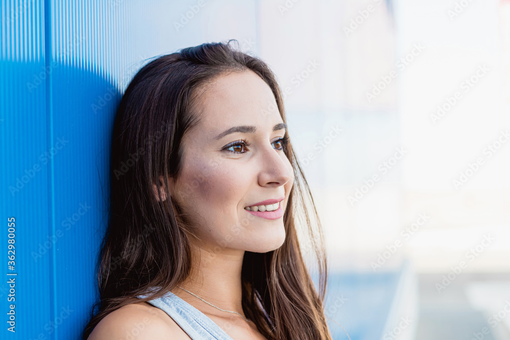 Face portrait of a beautiful young woman smiling with blue background