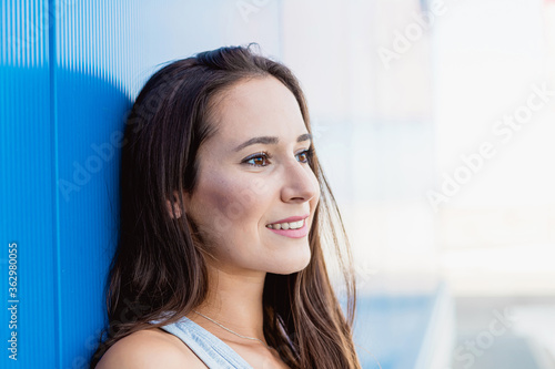 Face portrait of a beautiful young woman smiling with blue background