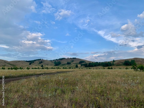 A stunning summer landscape with mountains, fields and forests. Beautiful sky.