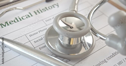 Patient medical history form on a table in a doctor or physician office. Stethoscope and pen on a paper used to record symptom and medicine that practitioner dispense or give to sick person in hospita