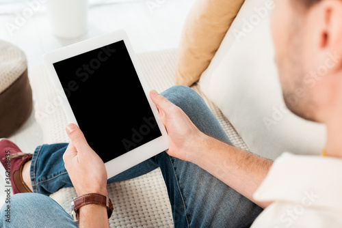 Selective focus of man holding digital tablet with blank screen on sofa