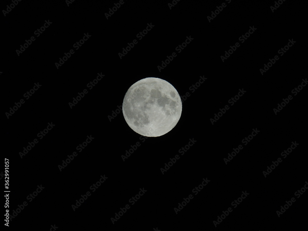 Genova, Italy - 07/05/2020: An amazing photography of the full moon over the city of Genova by night with a great clear and blue sky in the background and some stars. Genova, Italy - 07/05/2020: An amazing photography of the full moon over the city of Genova by night with a great clear and blue sky in the background and some stars.