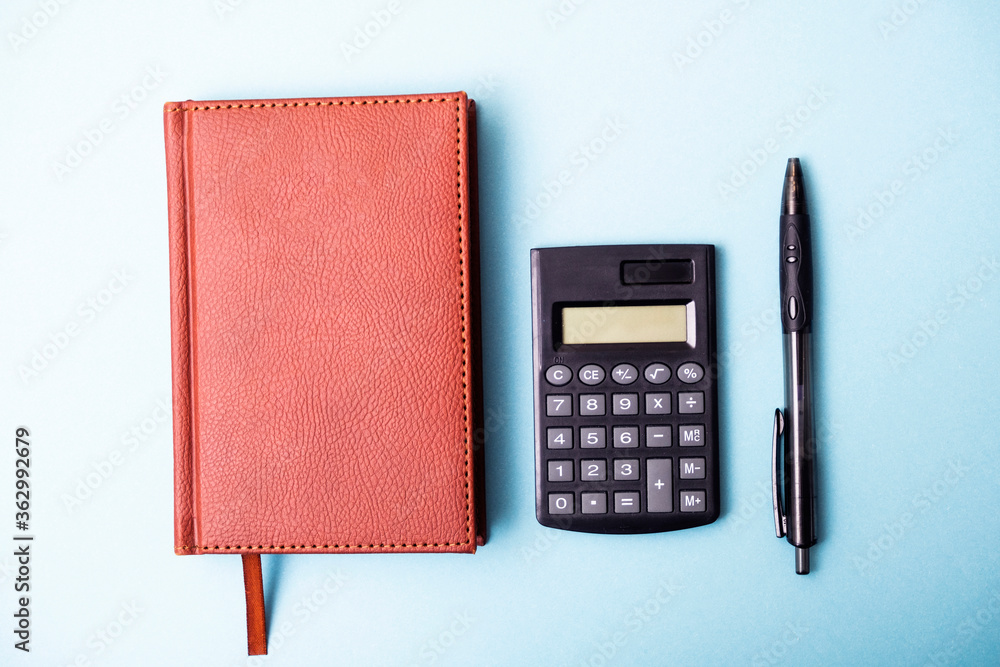 Diary, organizer, calculator and pen on a blue background. Notebook with  calculator and pen top view. Office tools. Stock Photo | Adobe Stock