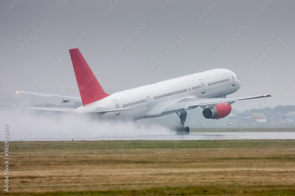 White passenger aircraft moves at the runway in heavy rain. Take-off with strong spray White passenger aircraft moves at the runway in heavy rain. Take-off with strong spray