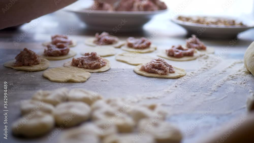 Beautiful elderly woman with wrinkled hands prepares dough on kitchen table. Knife, minced meat and condiments for pies. shallow depth of field Beautiful elderly woman with wrinkled hands prepares dough on kitchen table. Knife, minced meat and condiments for pies. shallow depth of field