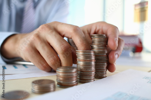 Close up of male hands building metal coins while working in the office. Business and strategy concept