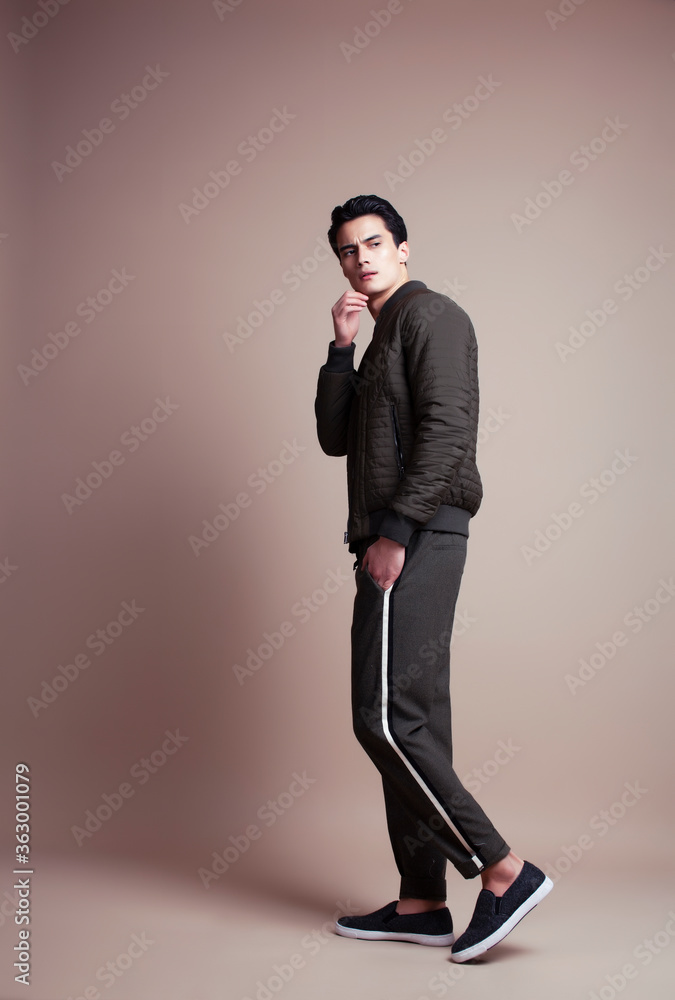 young pretty asian man posing in fashion style on light brown background, lifestyle people concept young pretty asian man posing in fashion style on light brown background, lifestyle people concept