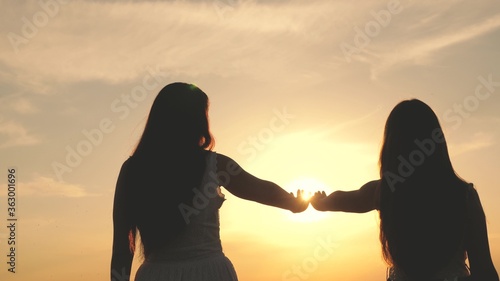 daughter and mother stretch their hands to sun. Happy family mom and daughter in field at sunset. concept of happy family of children . mother and baby are walking in park