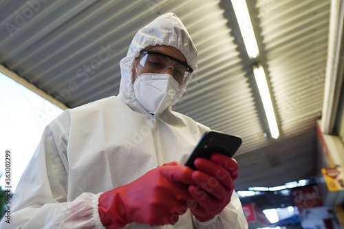 Low angle shallow focus shot of a person looking at a phone wearing protective clothing