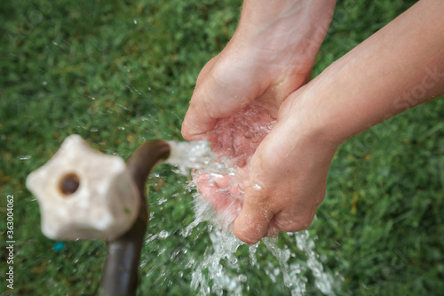 Hands washing under stream of water from faucet. A man washes his hands with tap water.