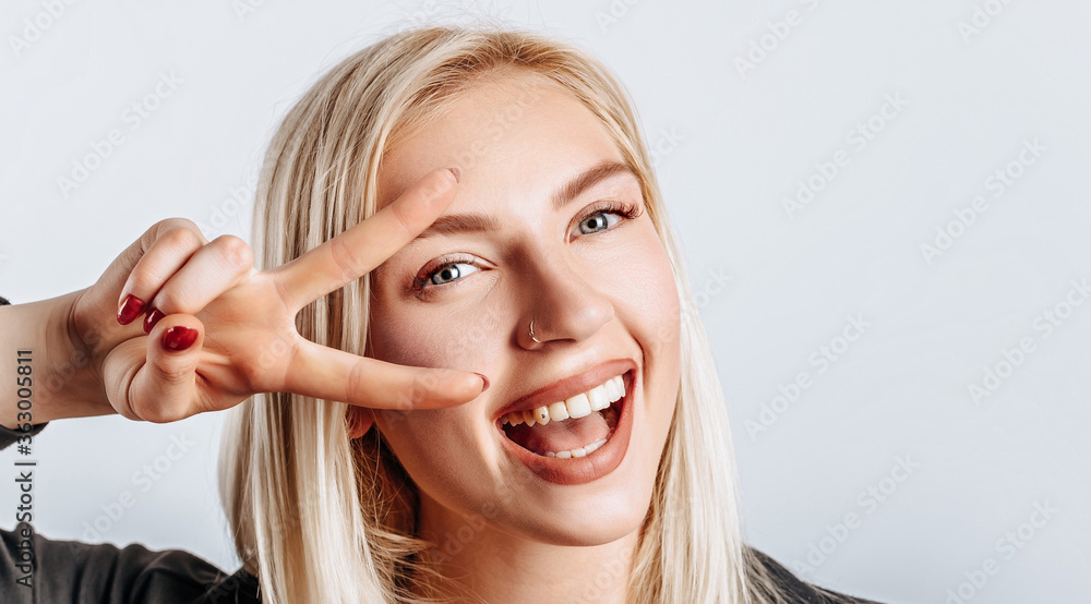 Hey smile you. Portrait of cheeky and cute glamor blond woman combed hair and jacket winking happily showing peace victory gesture as fooling around, being optimistic Hey smile you. Portrait of cheeky and cute glamor blond woman combed hair and jacket winking happily showing peace victory gesture as fooling around, being optimistic