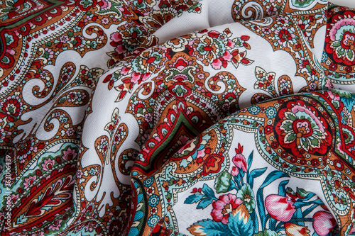 top view closeup on crumpled white cotton scarf with colorful paisley floral ornament