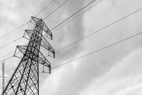 Trellis with electricity cables in a mountain environment. Dark clouds in the background. With copy space. Monochrome photo