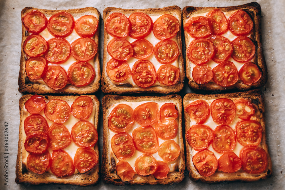 Baked sandwich with cheese and cherry tomatoes on dark bread.