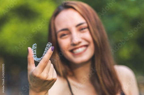 Beautiful smiling Turkish woman is holding an invisalign bracer with vibrant colors