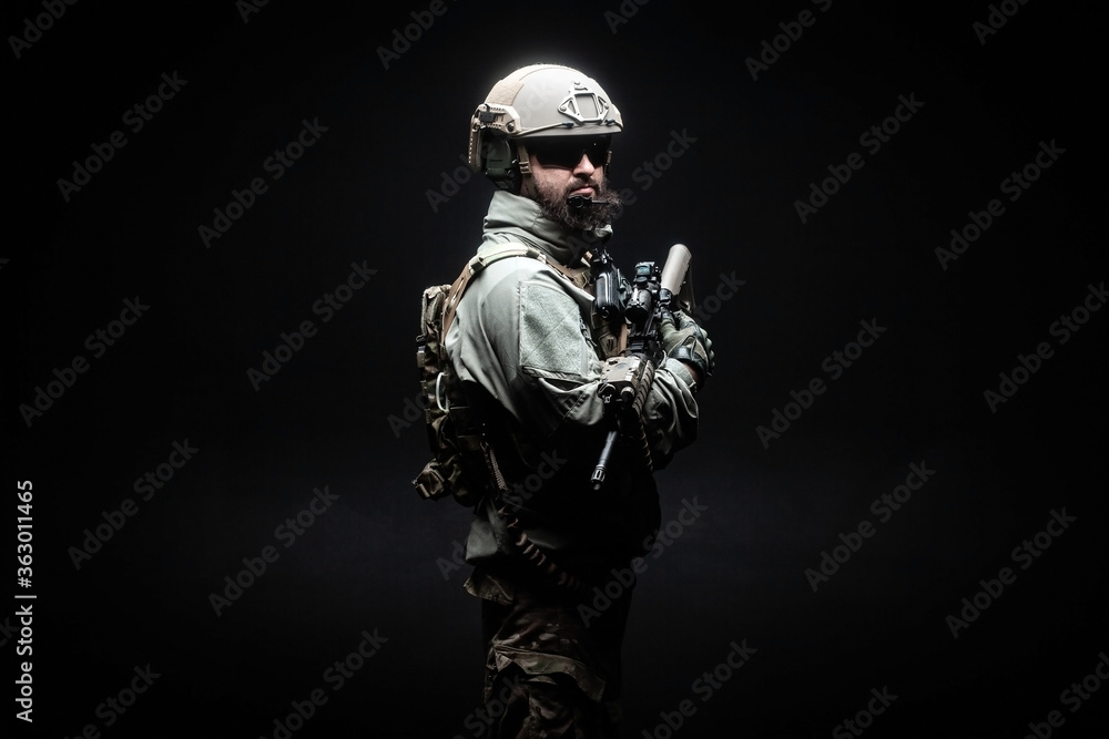 American soldier in military uniform with a weapon standing against a dark background, elite troops, American special forces