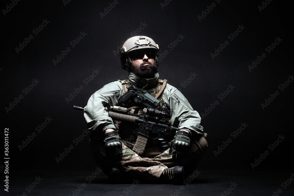 American soldier in a military uniform with a weapon sitting against a black background, elite troops of America, American special forces