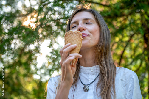 Portrait of young happy woman eating ice-cream. Cheerful young mom outdoor