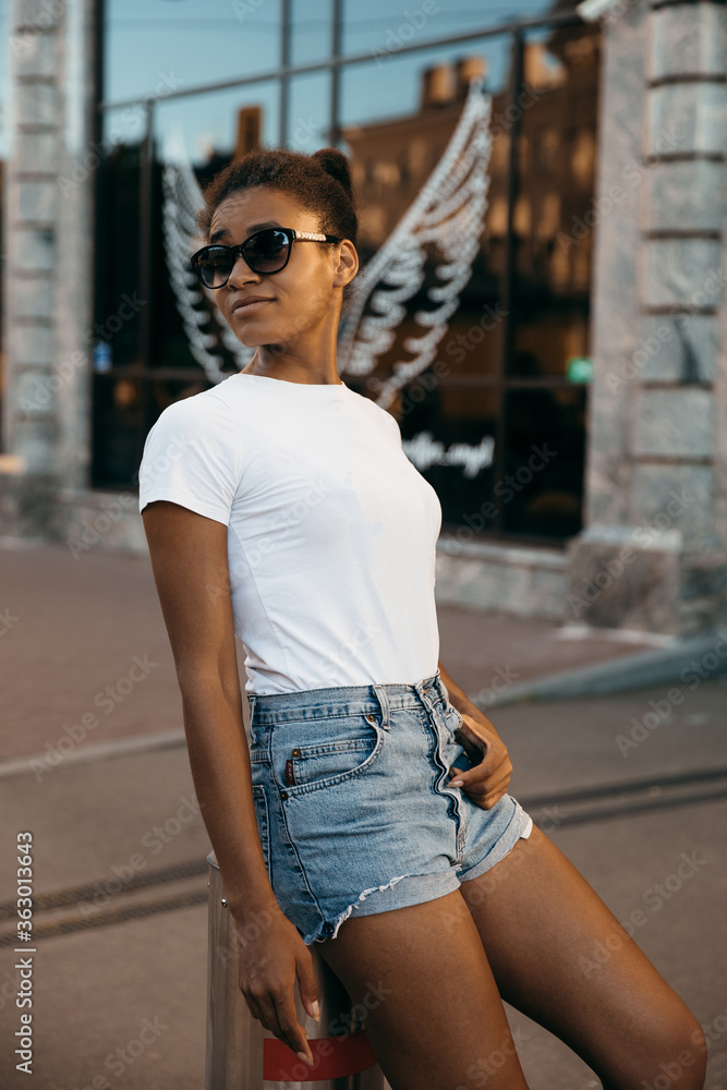 Urban afro american woman walking on the city street square on  sun