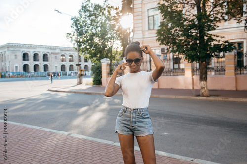 Urban afro american woman walking on the city street square on  sun © Anton