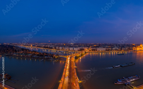 Aerial drone shot of Margaret Bridge with lights on over Danube river during Budapest sunset
