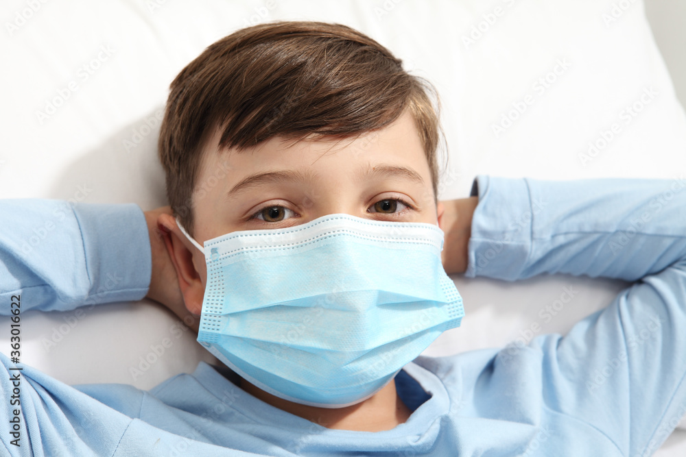 portrait of child with protective blue mask lying in bed, corona virus covid 19 protection concept, portrait of child with protective blue mask lying in bed, corona virus covid 19 protection concept,