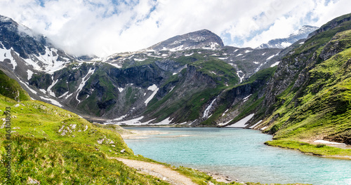 clear blue lake with painty green grass in the austrian alps in the Grossglockner area 