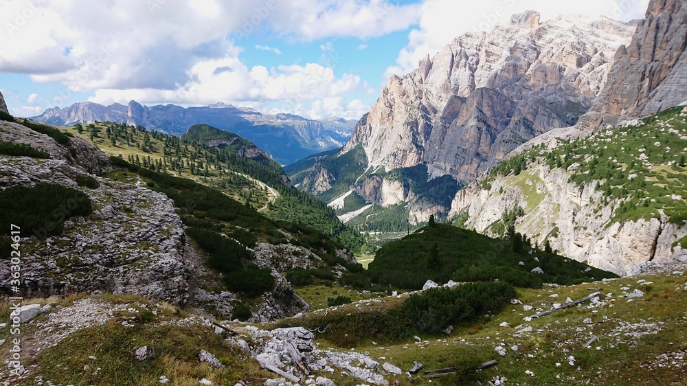 Landscape of dolomite Italian Alps, overgrown with green vegetation. On a summer day. Cloudy sky