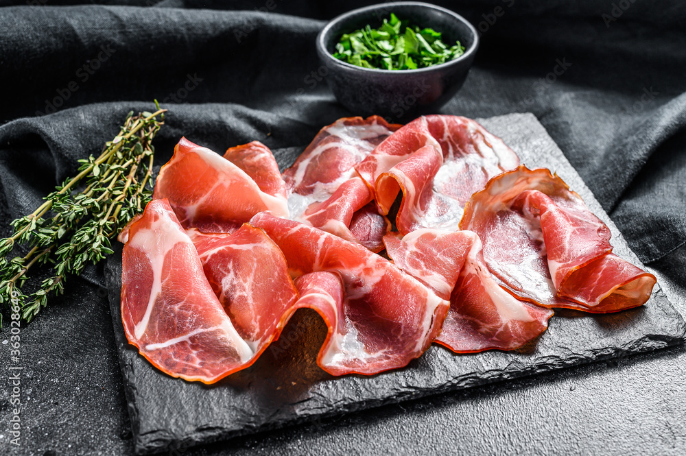 Italian rolled bacon Pancetta Piacentina. Pork meat. Black background. Top view