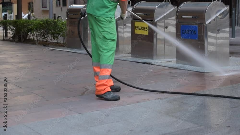 Street cleaning worker with pressure water gun, cleaning sidewalks, for prevention of covid19 in the streets of the municipality. Street cleaning worker with pressure water gun, cleaning sidewalks, for prevention of covid19 in the streets of the municipality.