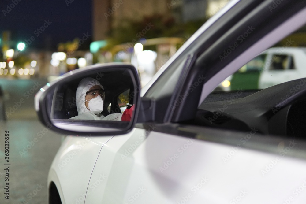 Shallow focus shot of a person with protective clothes riding a car, reflected in the car mirror