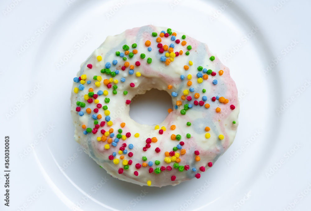 Donut, Slice of Food, Healthy Eating, Chart, Dieting. One donut with white icing served on white round plate. An overhead view of a doughnut with colored sprinkles. Unhealthy eating