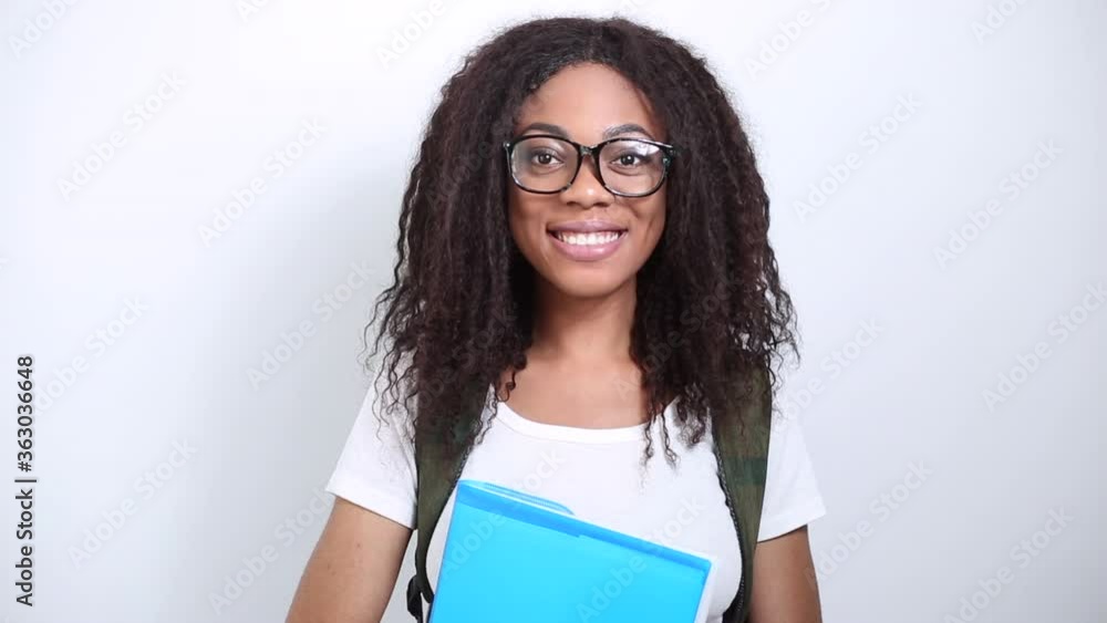 Portrait of a smiling African American young female student. Black happy girl in glasses with books on a white background. Portrait of a smiling African American young female student. Black happy girl in glasses with books on a white background.