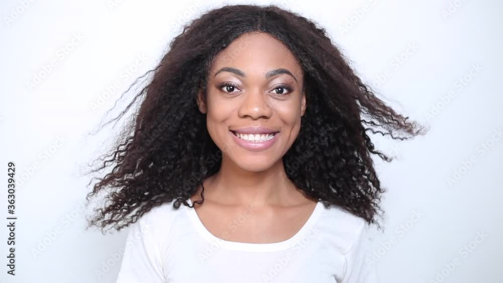 Close-up of smiling young African American young woman. The wind blows the hair of a black girl. Portrait of a happy female with curly hair. Close-up of smiling young African American young woman. The wind blows the hair of a black girl. Portrait of a happy female with curly hair.