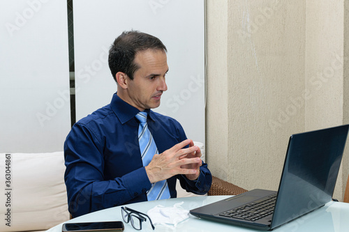 Mature man in formal clothes looking at the notebook with an insecure pusture.