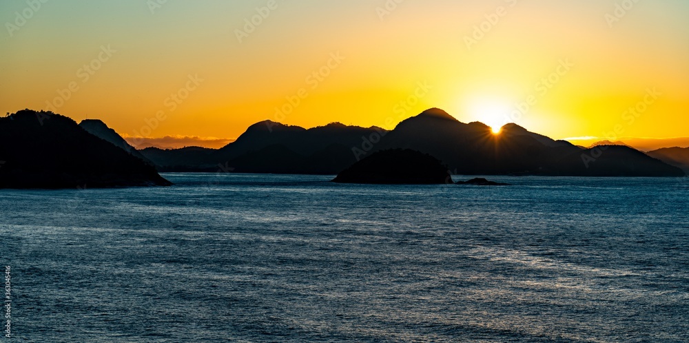 Silhouettes of seaside hills and rocks during sunset in Brazil