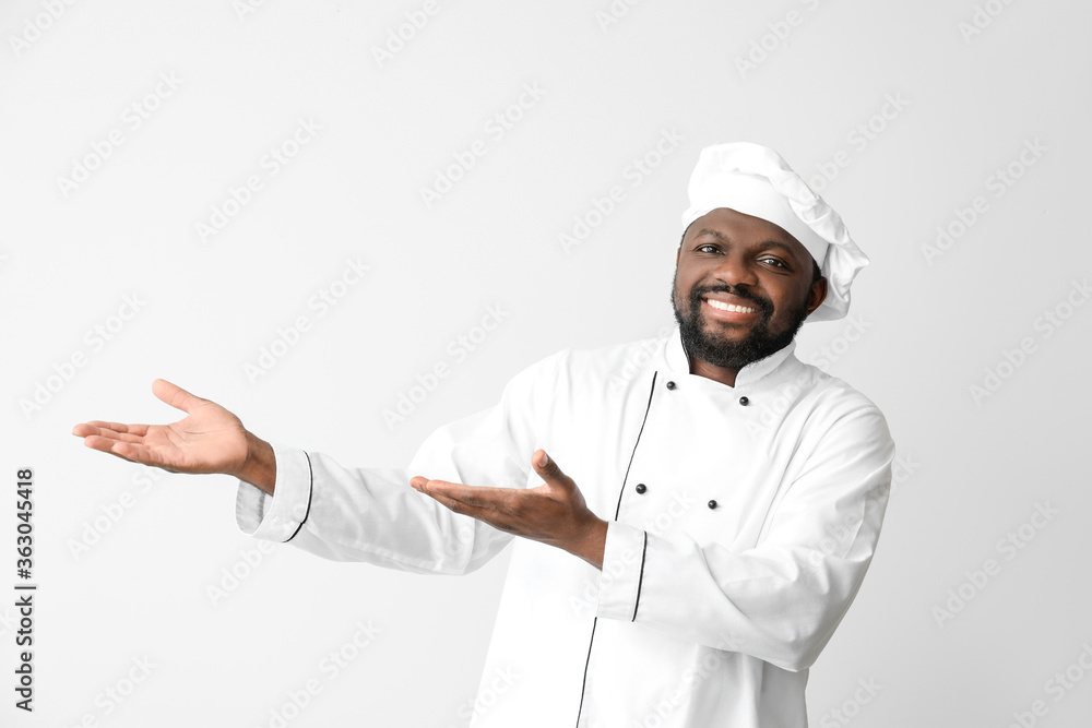 Male African-American chef showing something on white background Male African-American chef showing something on white background