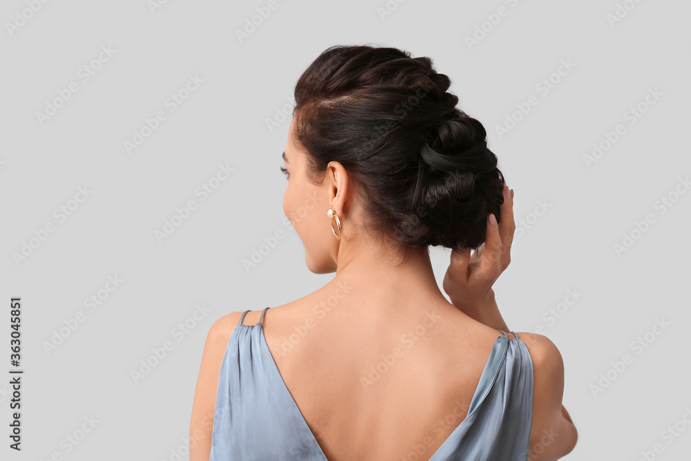 Beautiful young woman with stylish hairdo on grey background, back view Beautiful young woman with stylish hairdo on grey background, back view