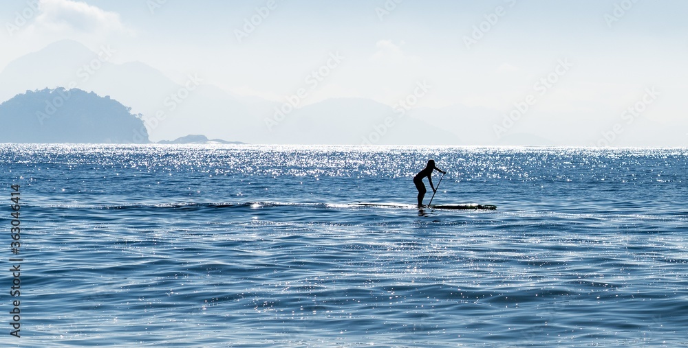 Silhouette of a woman stand up paddle surfing at the sea in Brazil
