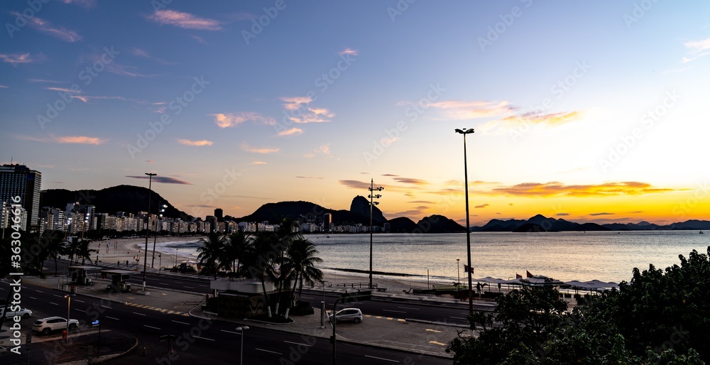 Beautiful view of the buildings and hills on the shore of the sea during sunset in Brazil