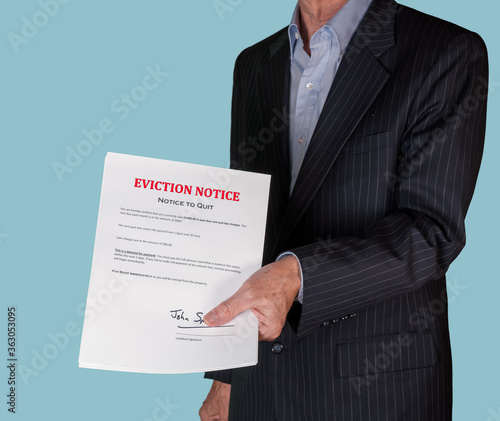 Man in suit serving an eviction notice to a defaulting renter in due to missed rent in recession photo