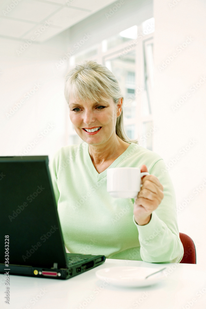 Woman holding a cup while using laptop Woman holding a cup while using laptop