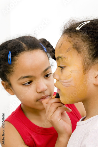 Girl painting her sister's face