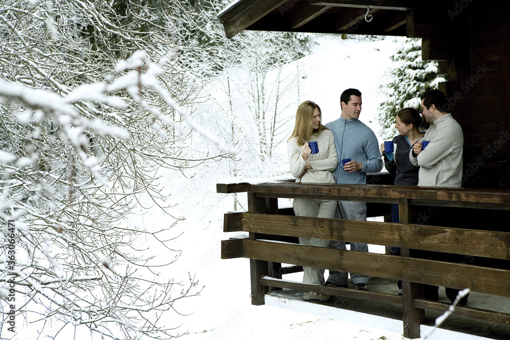 Two couples enjoying hot drinks in their chalet Two couples enjoying hot drinks in their chalet